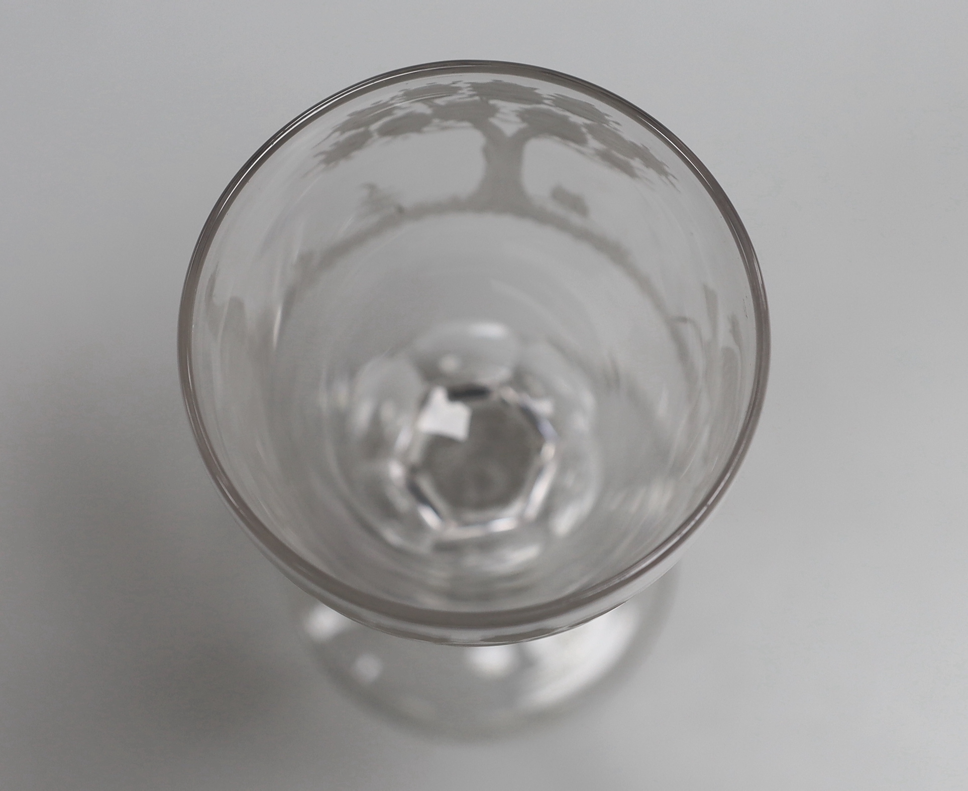 An English lead crystal facet stem goblet, c.1780, round funnel bowl, with hexagonal facet stem, conical foot, engraved in the round with trees and cock fighting scenes, 18.6cm